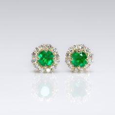 Two natural, round Colombian emeralds steal the spotlight in these Dainty Natural Emerald Stud Earrings. The emeralds are surrounded by a halo of brilliant-cut diamonds and set in platinum for enduring elegance and durability. SPECIFICATIONS: 1982752 Central stones: Two round, natural, Colombian emeralds. Dimensions: 4.15mm (average). Weight: 0.49ct. Side Stones:  24 Round Brilliant cut Diamonds, 1.5mm. Weight: 0.36ct.  Colour: F, Clarity: VS. Material: 18K Yellow Gold. Total Weight: 1.75 grams Green Diamond Round Cut Earrings, Green Fine Jewelry Cluster Earrings For Formal Events, Elegant Green Halo Earrings, Fine Jewelry Green Halo Earrings, Elegant Green Cluster Earrings With Prong Setting, Halo Green Fine Jewelry Earrings, Green Halo Earrings Fine Jewelry, Green Halo Earrings For Anniversary, Green Diamond Halo Design Earrings