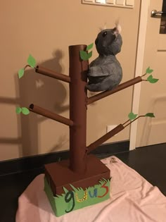 a stuffed koala bear sitting on top of a tree with leaves and branches attached to it