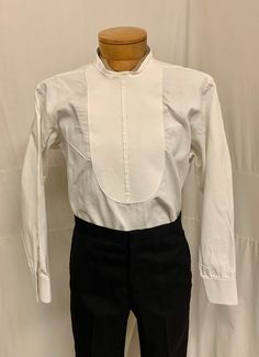 "1900, 15\" Neck, linen collarless shirt with pique front bib, with 3 stud button holes.  Shirt buttons  down back. Curved at each hip at Nottoway.  Sleeves are long and double French cuffs. Label reads Brook Brothers made in England. Measurements: neck 15\" Chest 44\" Shoulder to shoulder 17\" Shoulder to hem 31\" Sleeves 25\" Arm holes 9\" Mid section 44\" Condition excellent" Fitted Stand Collar Top For Daywear, Fitted Daywear Top With Stand Collar, Classic Shirt With Stand Collar And Placket, Classic Shirt With Stand Collar And Buttons, Fitted Dress Shirt With Buttons For Daywear, Classic Tops With Stand Collar And Button Cuffs, Classic Stand Collar Tops With Buttons, Classic Tops With Button Cuffs And Stand Collar, Formal Cotton Top With Stand Collar