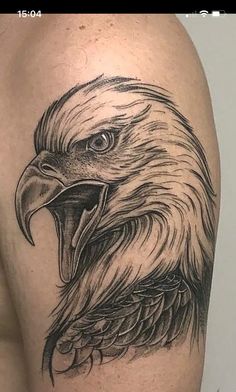 an eagle head tattoo on the back of a man's arm and shoulder,