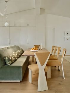 a living room filled with furniture next to a dining table and couch in front of a white wall