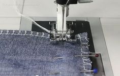 the sewing machine is working on some blue jeans that have been sewn together and are stitched together