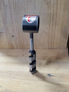 a small metal object on top of a wooden table next to a wall with wood planks