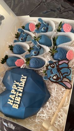 a birthday cake with blue frosting and pink roses on it in a box next to some cookies