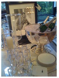 a table topped with lots of wine glasses and champagne bottles in front of a window