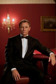 a man in a tuxedo sitting on a red chair