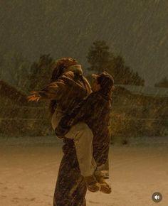 two people walking in the snow with an umbrella over their heads and one person carrying another