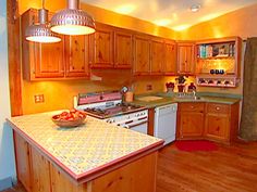 a kitchen with wooden cabinets and an island in the middle of the room, has a bowl of fruit on top of it