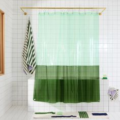 a green shower curtain in a bathroom with white tiled walls and flooring on the wall