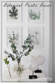 three vases filled with flowers sitting on top of a table next to framed pictures