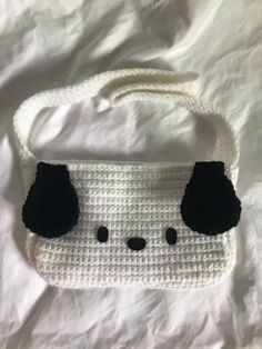 a white crocheted purse with black pom poms