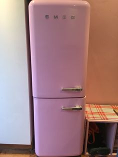 an old purple refrigerator sitting next to a white freezer in a room with wood flooring