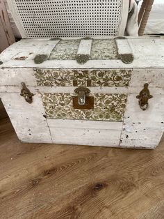 an old white trunk sitting on top of a wooden floor