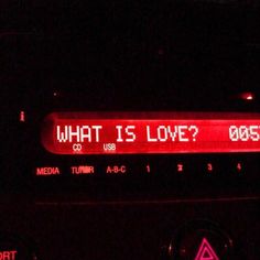 an electronic device with the words what is love written on it in red light at night