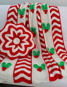 red and white crocheted afghan with green accents on it, sitting on a couch