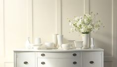 a white dresser with vases and flowers on it