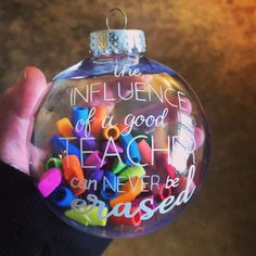 a hand holding a glass ornament with writing on it that says, the influence of a good teach can never be passed