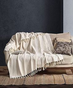 a couch covered in a blanket on top of a wooden floor