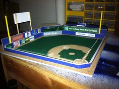 a model baseball field in the shape of a stadium with stands and signs on it