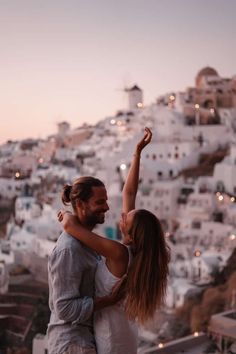 a man and woman standing on top of a hill with their arms in the air