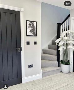 a white vase with flowers sitting on the floor next to a black and white door