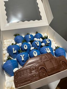 a box filled with blue and white cupcakes in the shape of trucks next to each other