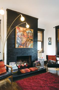 a living room with black brick walls and red rugs on the floor next to a fire place