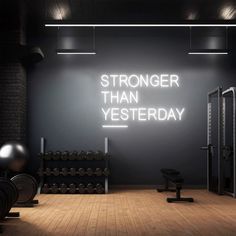 an exercise room with neon signs on the wall that says,'stronger than yesterday '