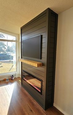 an empty room with a television mounted on the wall and wood flooring in front of it