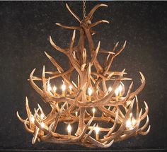 a chandelier made out of antlers with candles in the middle of it