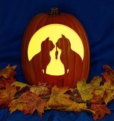 a pumpkin carved to look like a dog and cat kissing in front of a full moon