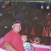 an old photo of a man holding a small child in front of a carnival ride