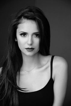 a black and white photo of a woman with long dark hair wearing a tank top