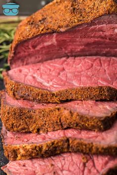 sliced roast beef on a cutting board with herbs and seasoning next to the meat