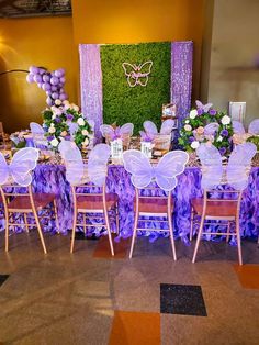 a table set up with purple and white decorations for a butterfly themed birthday or baby's first birthday party