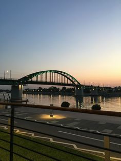 a bridge that is over some water at sunset or dawn with the sun setting behind it