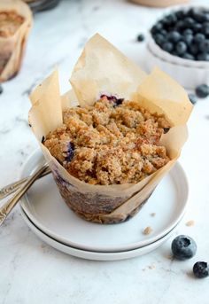 a muffin on a plate with some blueberries