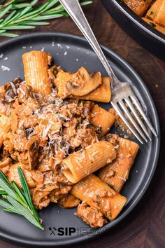 a black plate topped with pasta and meat