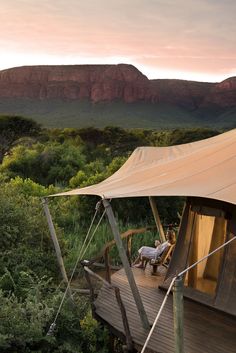 an outdoor tent with trees and mountains in the background