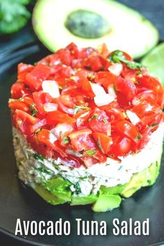 an avocado tuna salad with tomatoes and cucumbers on a black plate