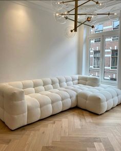 a large white couch sitting in the middle of a living room next to a window