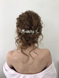 the back of a woman's head wearing a wedding hair comb with flowers in it