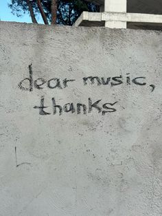 graffiti written on the side of a cement wall saying dear music, thanks to someone