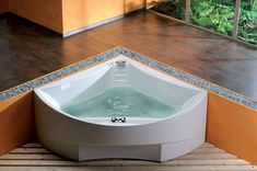 a large white bath tub sitting on top of a wooden floor next to a wall