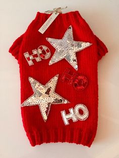 a red dog sweater with silver stars and ho ho written on the front in white letters