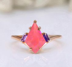 Ring Specifications & Details: Engagement/Wedding/Bridal Ring Stone Size: 12.00 X 8.00 mm Side Gemstone:  Amethyst Stone Type: Lab Created Pink Opal Gemstone Metal Used: 925 Sterling Silver Plating Available: Rhodium/ Yellow/ Rose Gold We apply 2.5 micron of thicker plating on our rings. Stone CTW: 3.10 ctw  SKU: RG8952  You may also favorite our studio for continuous updates on new designs and special discount coupons. Their would be special sale in the beginning of every month.  We work in all semi precious and precious gemstones so you may reach to us if you want any particular gemstone in this jewelry article. We can also make custom product for you. Pink Opal Rings With Gemstone, Pink Fire Opal Engagement Ring, Luxury Pink Opal Ring Gift, Luxury Pink Opal Ring, Baguette Rings, Elegant Iridescent Cabochon Opal Ring, Rings Stone, Opal Engagement Ring, Pretty Wedding Dresses