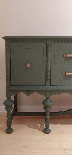 a green dresser sitting on top of a hard wood floor next to a white wall