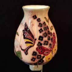 a white vase with butterflies painted on it