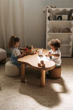 two children sitting at a table playing with toys