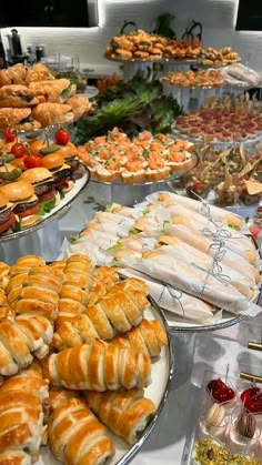 many different types of pastries are on display at a buffet table with white linens